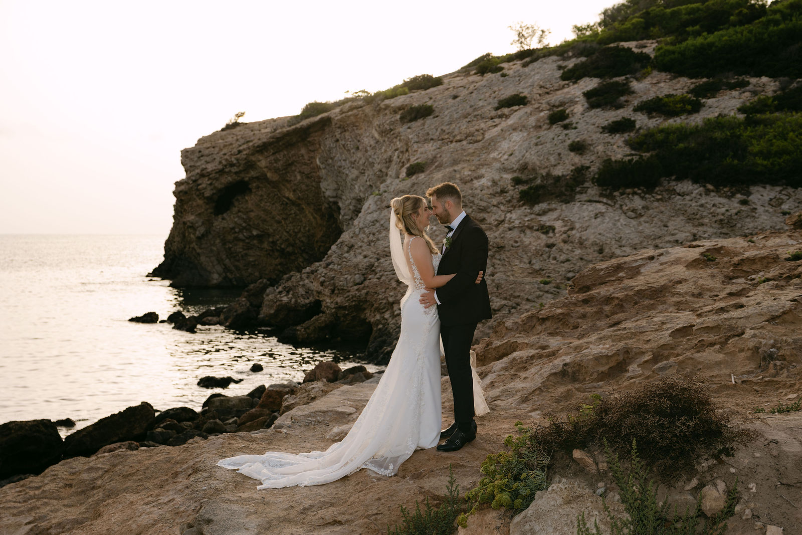 Couple embracing on Ibiza cliffs at golden hour — luxury wedding content